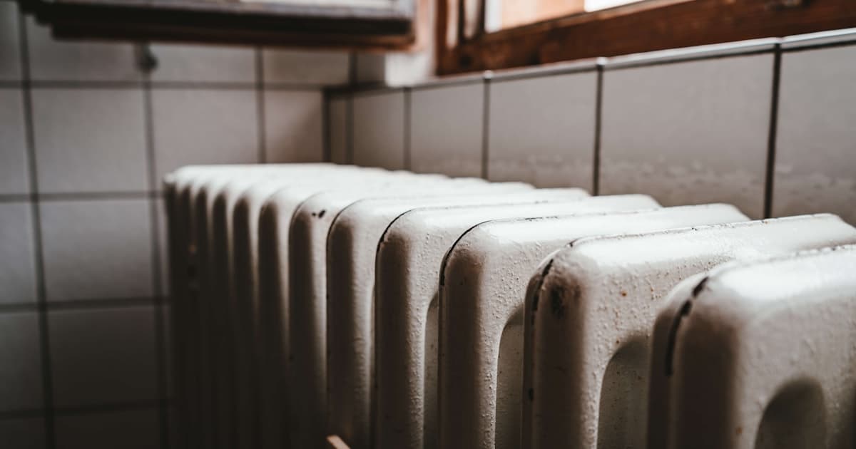 Litinový radiátor u okna — klasické vytápění v bytovém domě