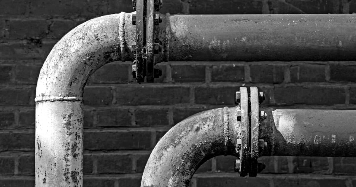 Stoupací potrubí na cihlové zdi — rozvody vody v bytovém domě